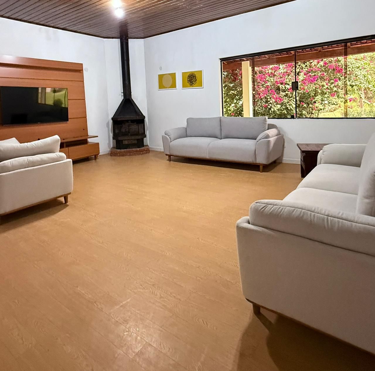 Sala de convivência com sofás, almofadas, plantas e estante de livros