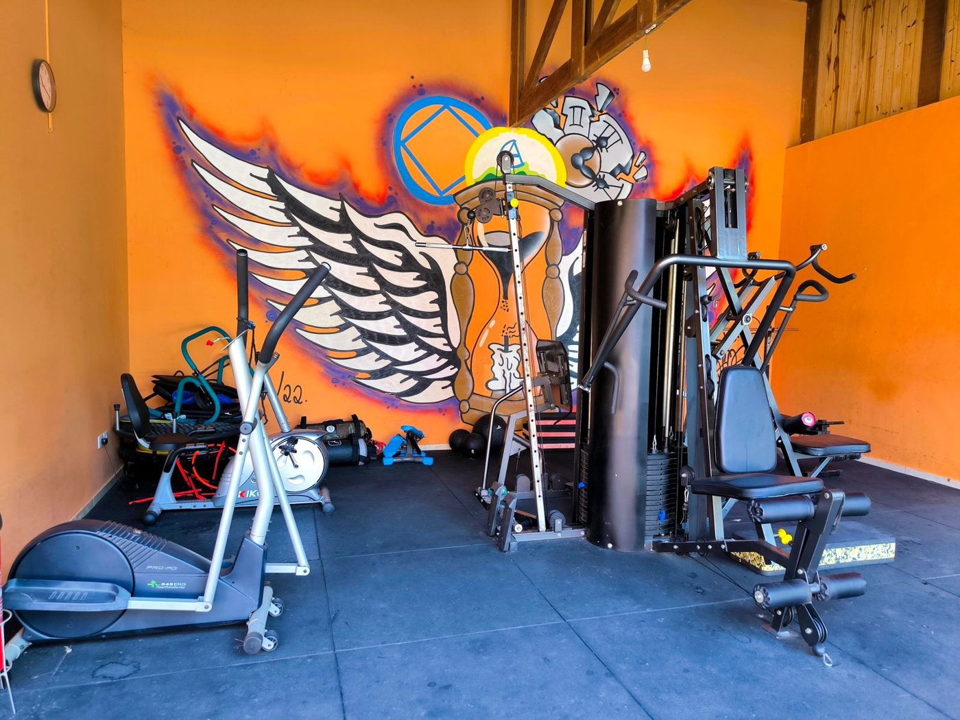 Espaço de atividades físicas com aparelhos de musculação e bicicleta ergométrica
