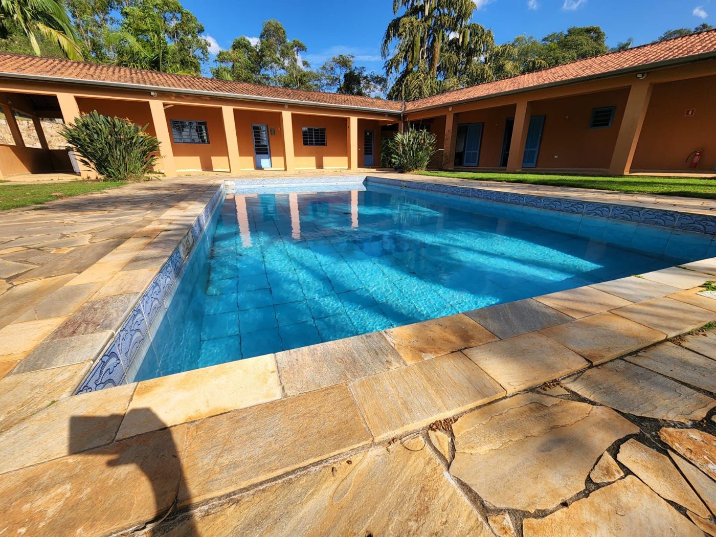 Piscina ao ar livre com deck amplo em unidade masculina cercada por área verde