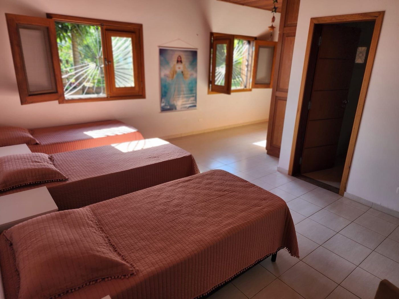 Quarto compartilhado organizado, com camas de solteiro e janelas com vista para o jardim